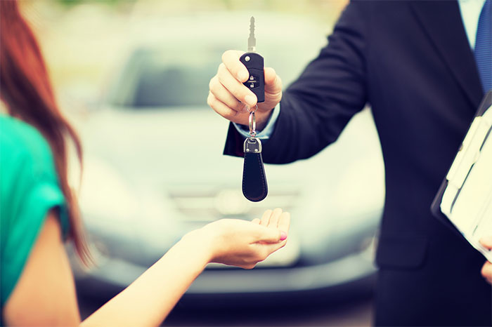 car-salesman-handing-keys-to-female-driver-main-2